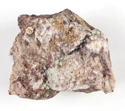 Fotografia różowo-białego minerału z okrągłą etykietą na białym tle