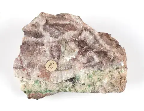 Fotografia minerału: nieregularny kamień z brązowymi kryształami, zielonym paskiem i żółtą etykietą