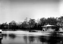 Czarno-biała fotografia nabrzeża z pawilonem, willami i spokojną taflą wody